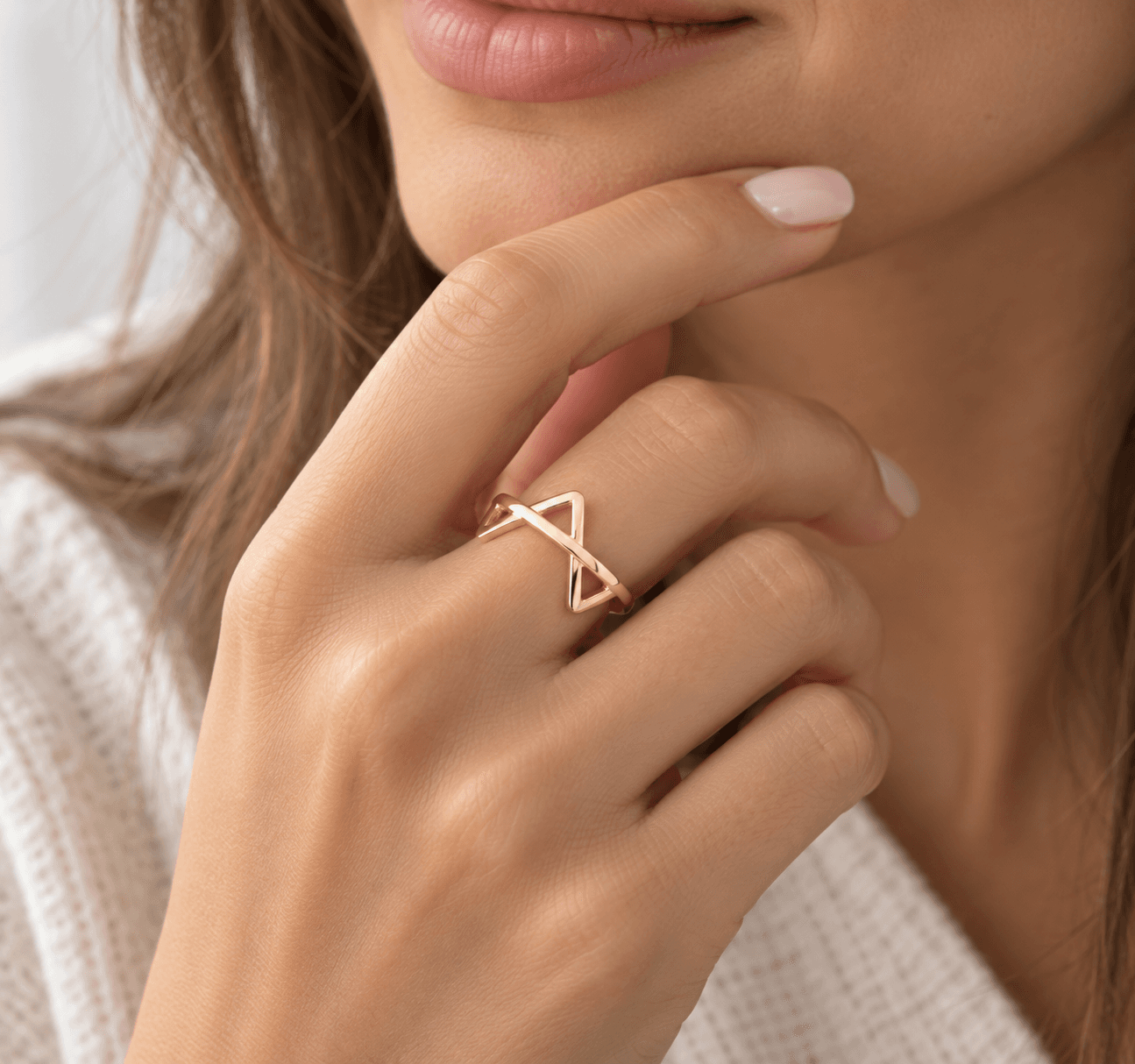 A hand raised to the chin, wearing one gold vermeil piece on its own.